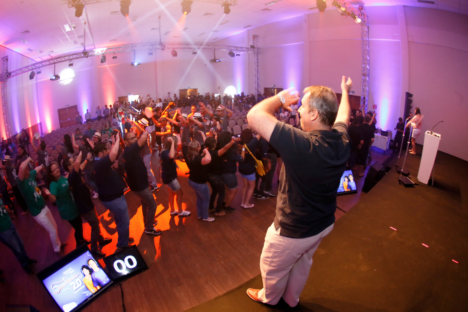 Evento com iluminação roxa e plateia participando